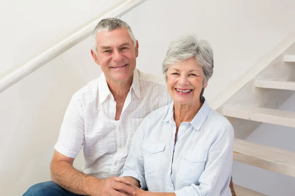 Senior couple sitting on stairs smiling at camera — Stock Photo, Image