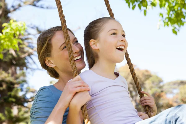 Happy mother swinging daughter at park — Stock Photo, Image