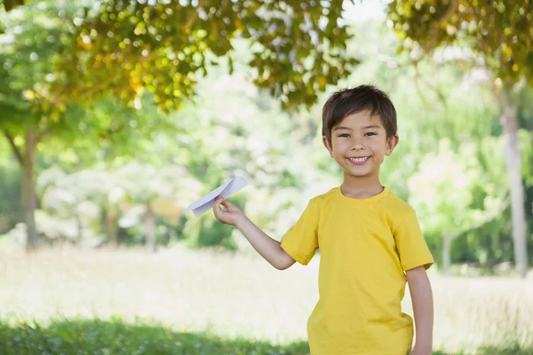 Gelukkige jongen speelt met een papieren vliegtuig in het park — Stockfoto