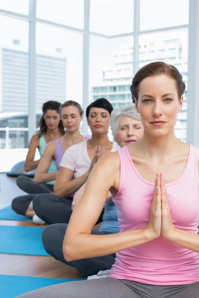 Klasse zitten met gekoppelde handen in een rij op yoga klas — Stockfoto