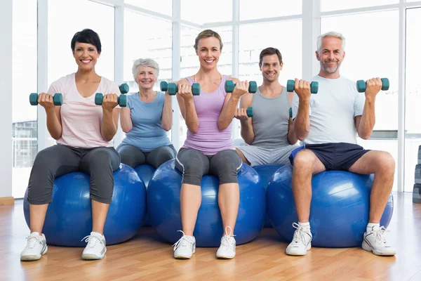 Aula de fitness com halteres sentados em bolas de exercício — Fotografia de Stock