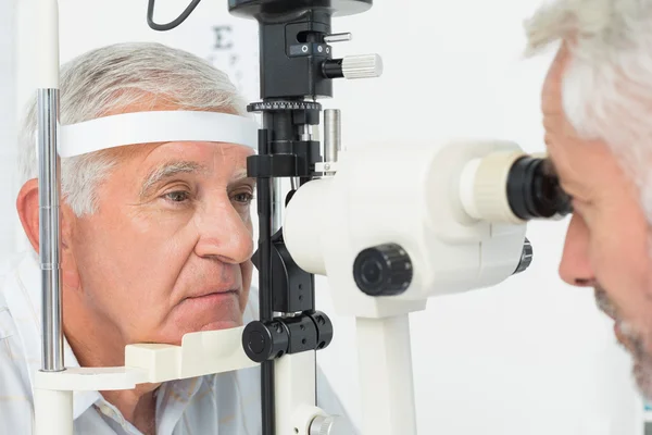 Optometrista fazendo teste de visão para paciente sênior — Fotografia de Stock