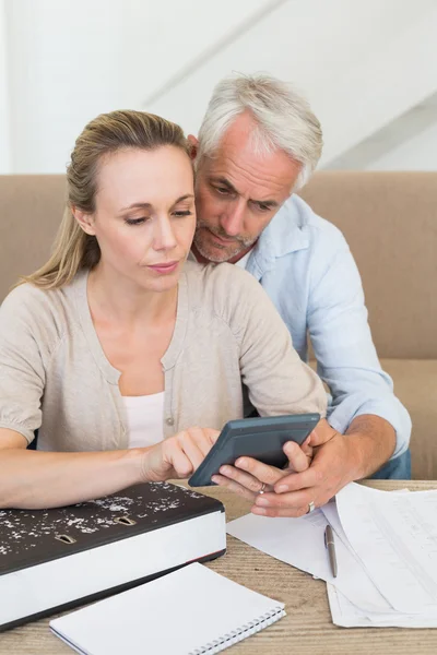 Serious couple calculating their bills at the couch — Stock Photo, Image