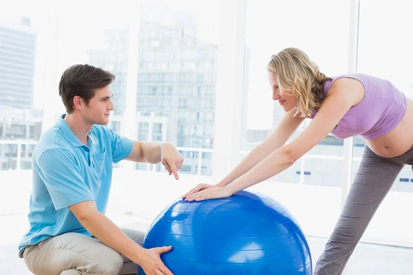 Pregnant woman exercising with trainer — Stock Photo, Image