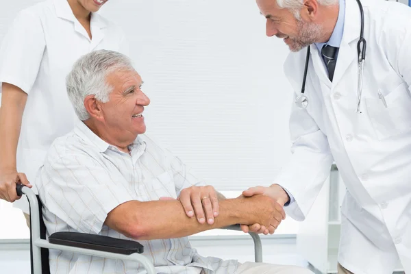 Uśmiechający się starszy pacjent i lekarz drżenie rąk — Zdjęcie stockowe