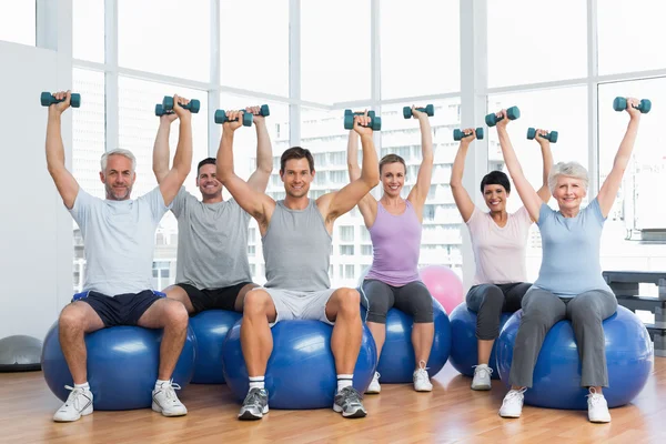 Lezione di fitness con manubri seduti su palline in palestra — Foto Stock