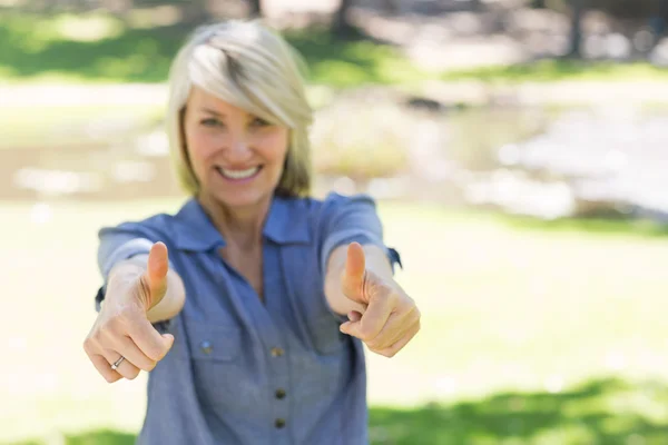 Woman gesturing thumbs up in park — Stock Photo, Image