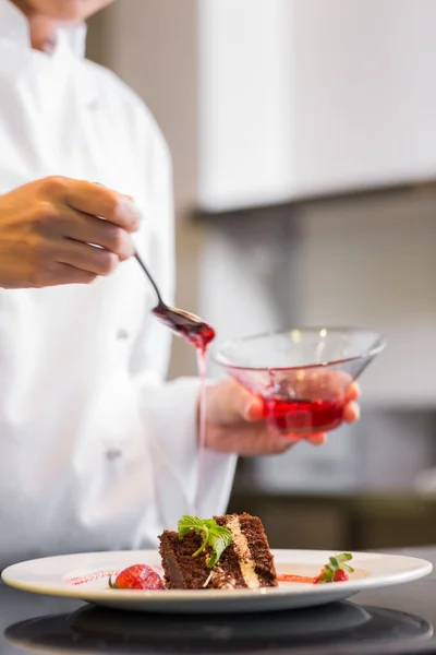 Mitten delen av konditor dekorera desserten i köket — Stockfoto