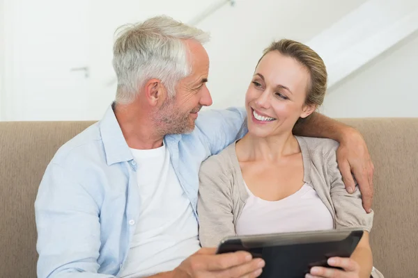 Casal feliz usando tablet pc juntos no sofá — Fotografia de Stock