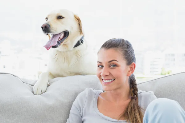 Happy woman posing with her yellow labrador on the couch — Stock Photo, Image