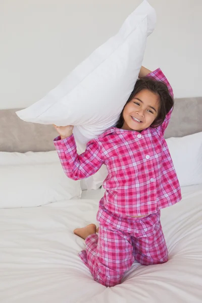 Mädchen hält ein Kissen im Bett hoch — Stockfoto