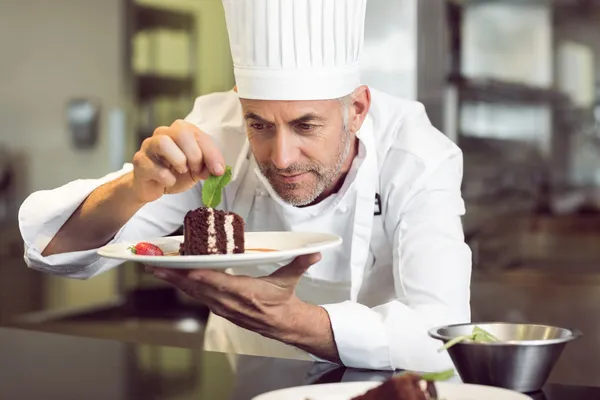 Concentrado chef pasteleiro masculino decoração sobremesa na cozinha — Fotografia de Stock