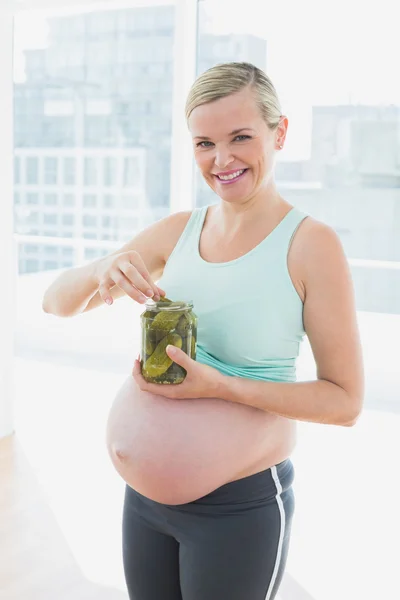 Lachende blonde zwangere vrouw eten uit pot Pickles — Stockfoto