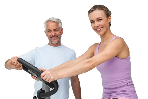 Portrait of a happy woman on stationary bike with trainer — Stock Photo, Image