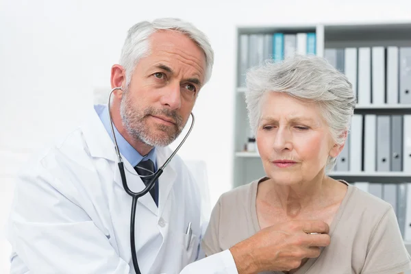 Médico revisando pacientes latidos del corazón usando estetoscopio —  Fotos de Stock