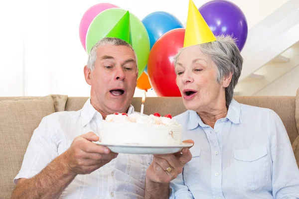 Pareja mayor sentada en un sofá celebrando un cumpleaños —  Fotos de Stock
