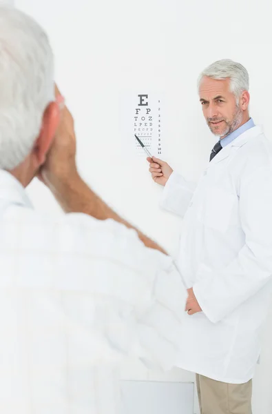 Pediatrician ophthalmologist with senior patient pointing at eye — Stock Photo, Image