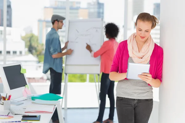 Artist using digital tablet with colleagues in background — Stock Photo, Image