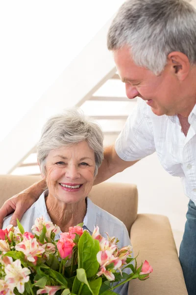 Senior mannen att ge sin partner en bukett blommor leende — Stockfoto