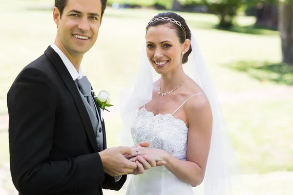 Brudgummen att placera ringen på brudar finger på park — Stockfoto