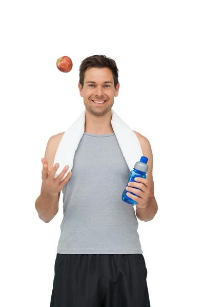 Smiling fit young man with apple and water bottle — Stock Photo, Image