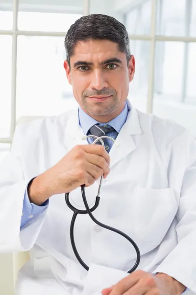 Médico masculino grave segurando estetoscópio — Fotografia de Stock