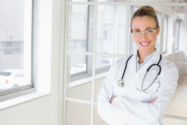 Beautiful female doctor with arms crossed in hospital — Stock Photo, Image