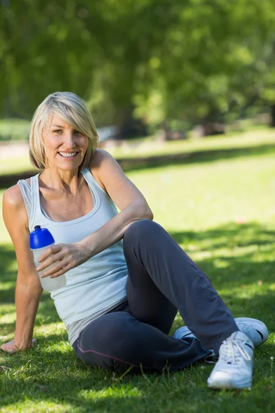 Sportovní žena drží láhev vody v parku — Stock fotografie