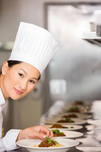 Femme chef souriante garnissant la nourriture dans la cuisine — Photo