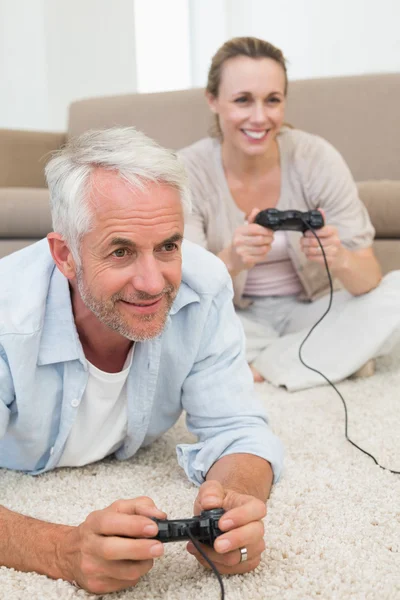 Sorrindo casal deitado no tapete jogando videogames — Fotografia de Stock