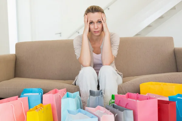 Żal kobieta patrząc na wiele torby na zakupy na kanapie — Zdjęcie stockowe