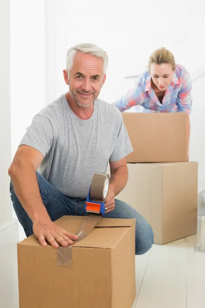 Happy couple sealing cardboard moving boxes — Stock Photo, Image