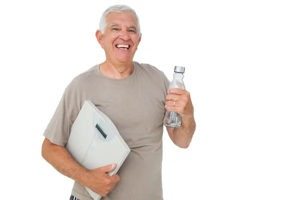 Веселый пожилой человек с бутылкой воды и весами — стоковое фото