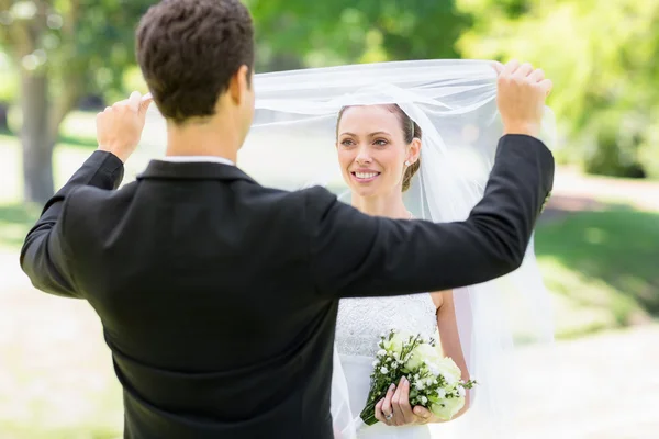 Amoroso noivo véu de elevação da noiva — Fotografia de Stock
