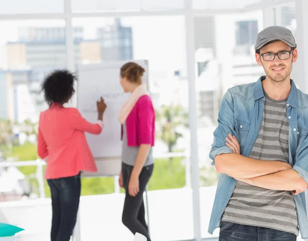 Artiste masculin occasionnel avec des collègues en arrière-plan au bureau — Photo