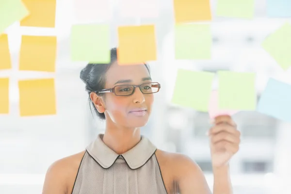 Jonge ontwerper kijken naar plaknotities op venster — Stockfoto