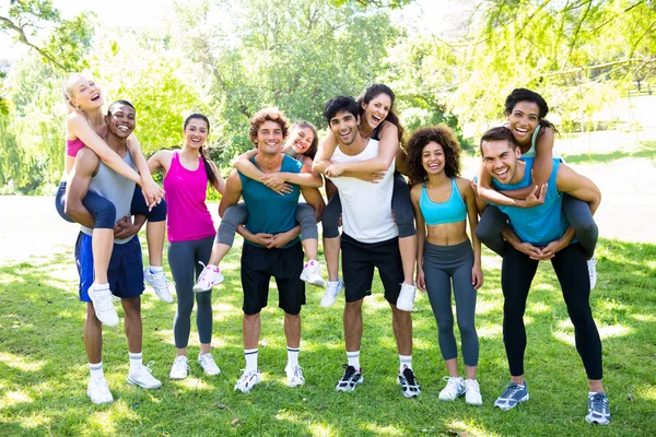 Men piggybacking friends in the park — Stock Photo, Image