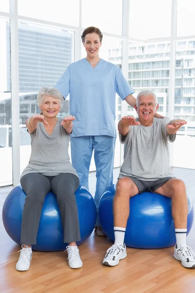 Therapist assisting senior couple with exercises — Stock Photo, Image