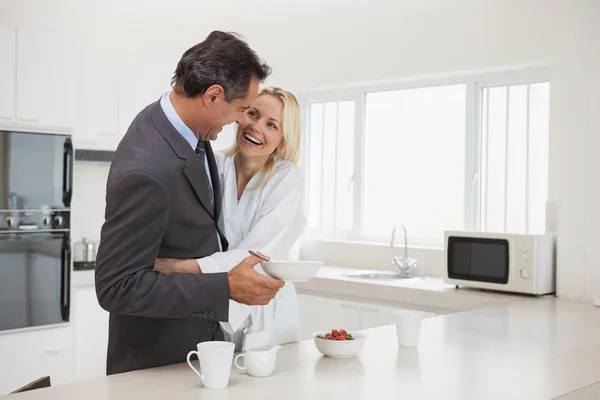 Woman embracing businessman in the kitchen — Stock Photo, Image