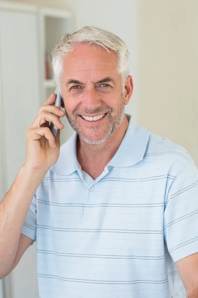 Homme souriant sur un appel téléphonique regardant la caméra — Photo