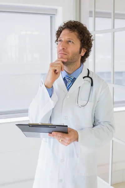 Thoughtful male doctor with reports in hospital — Stock Photo, Image