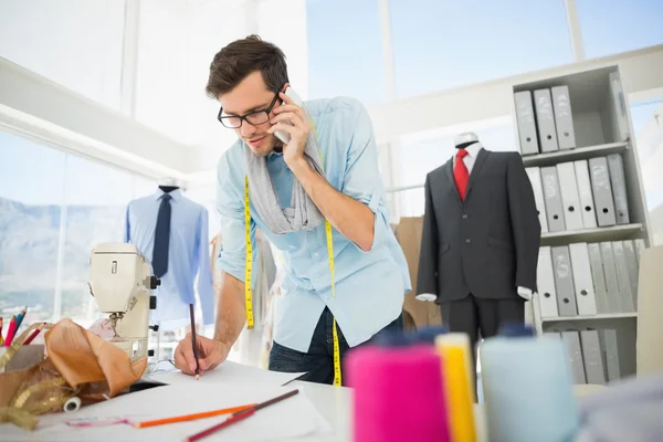 Fashion designer working on his designs while on call — Stock Photo, Image