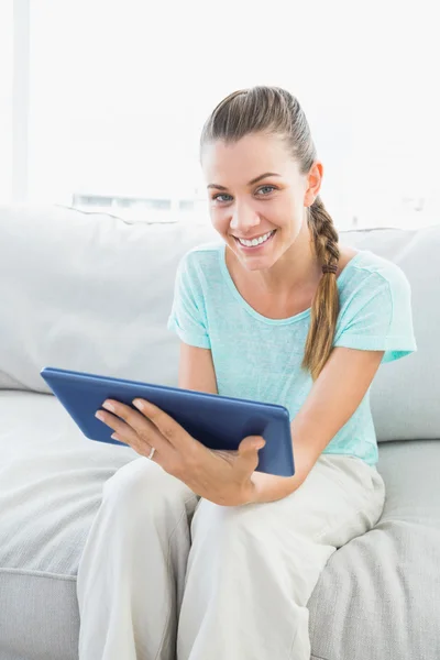 Mujer sonriente sentada en el sofá usando tableta pc — Foto de Stock