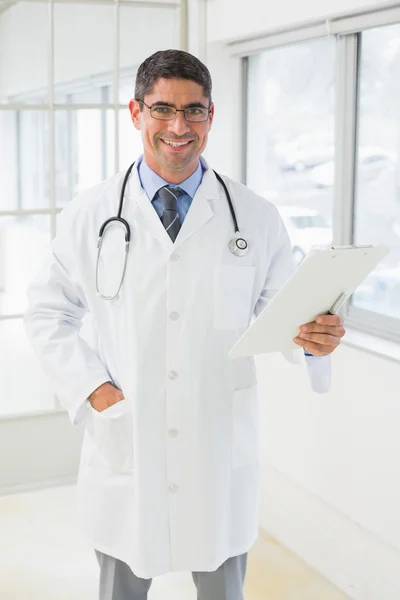 Smiling male doctor holding reports in hospital — Stock Photo, Image