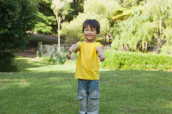 Young boy gesturing thumbs up in park — Stock Photo, Image