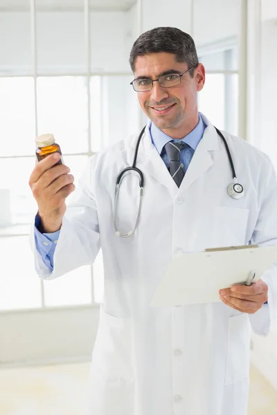 Smiling male doctor with a bottle of pills in hospital — Stock Photo, Image