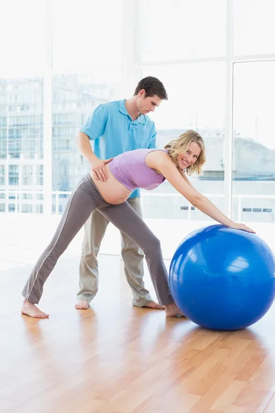 Pregnant woman exercising with trainer — Stock Photo, Image