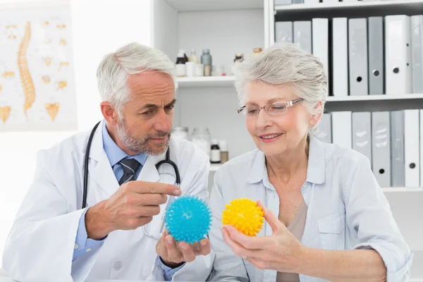 Doctor mostrando pelotas de estrés a paciente mayor — Foto de Stock