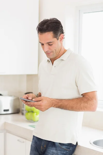 Man van het tekstoverseinen in keuken — Stockfoto