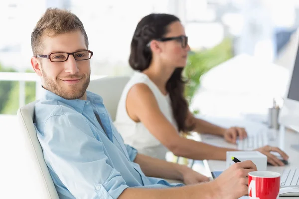 Handsome designer smiling at camera at desk — Stock Photo, Image